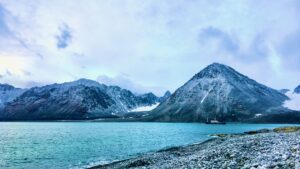 A ship sailing along the mountainous coastline in the Svalbard area in the Arctic