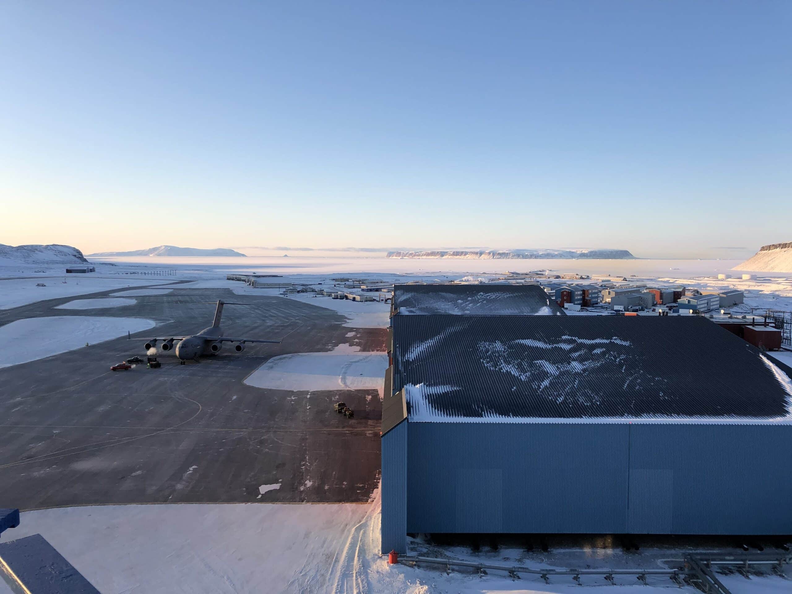 The afternoon sun shines low on Pituffik Space Base, Greenland, and a single C-17 transport aircraft on the airfield