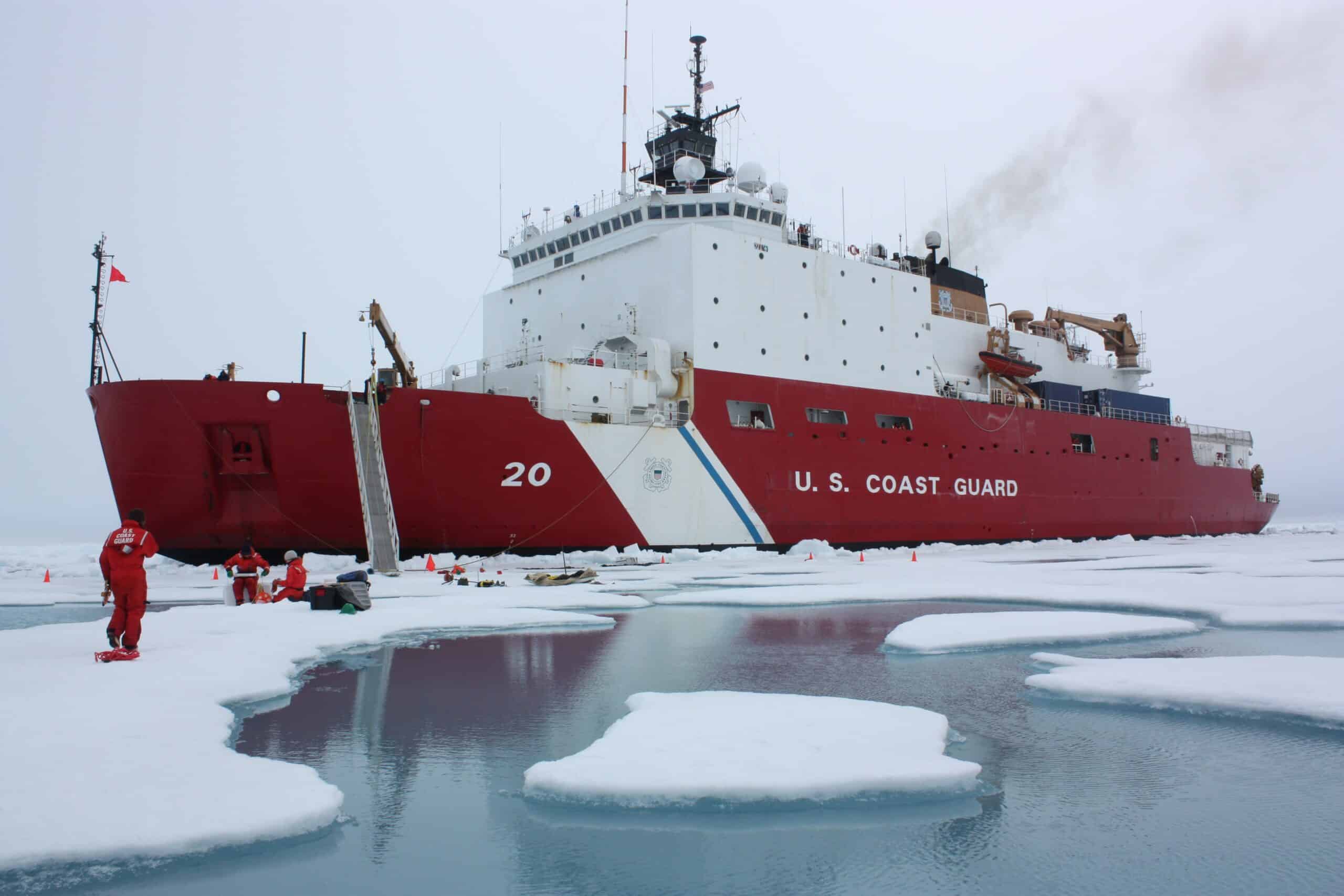 A red US Coast Guard ship in ice and gray water against a white sky