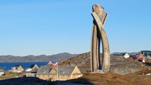 Colourful Greenlandic houses and traditional Inuit monument overlooking at harbour