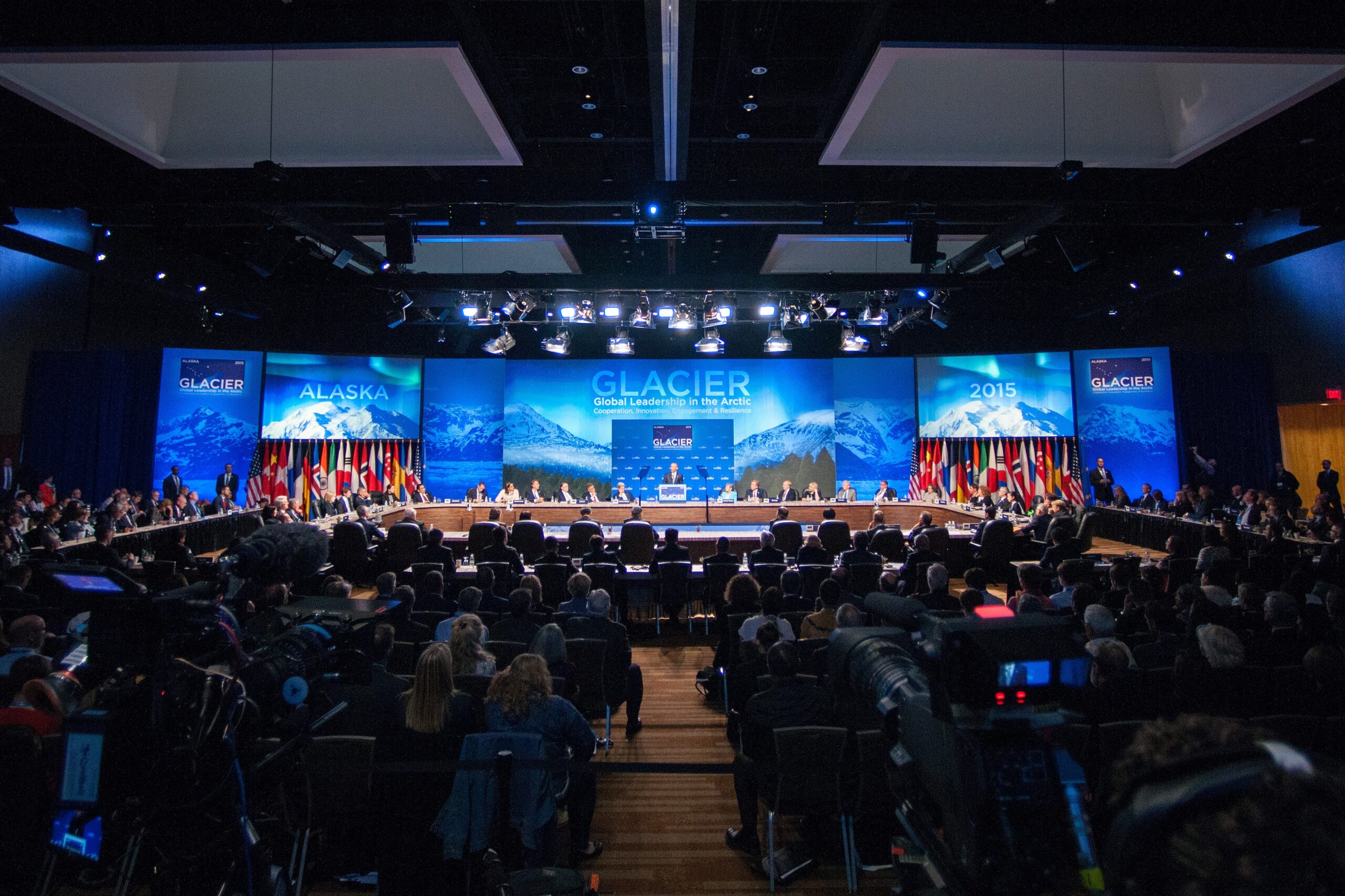 Round table of people with a backdrop that states GLACIER and audience members in foreground