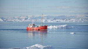 A boat sails amidst sea ice on the coast of Greenland